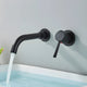 Mitigeur mural encastré noir mat au-dessus d'une baignoire, bec et manette sur rosaces rondes