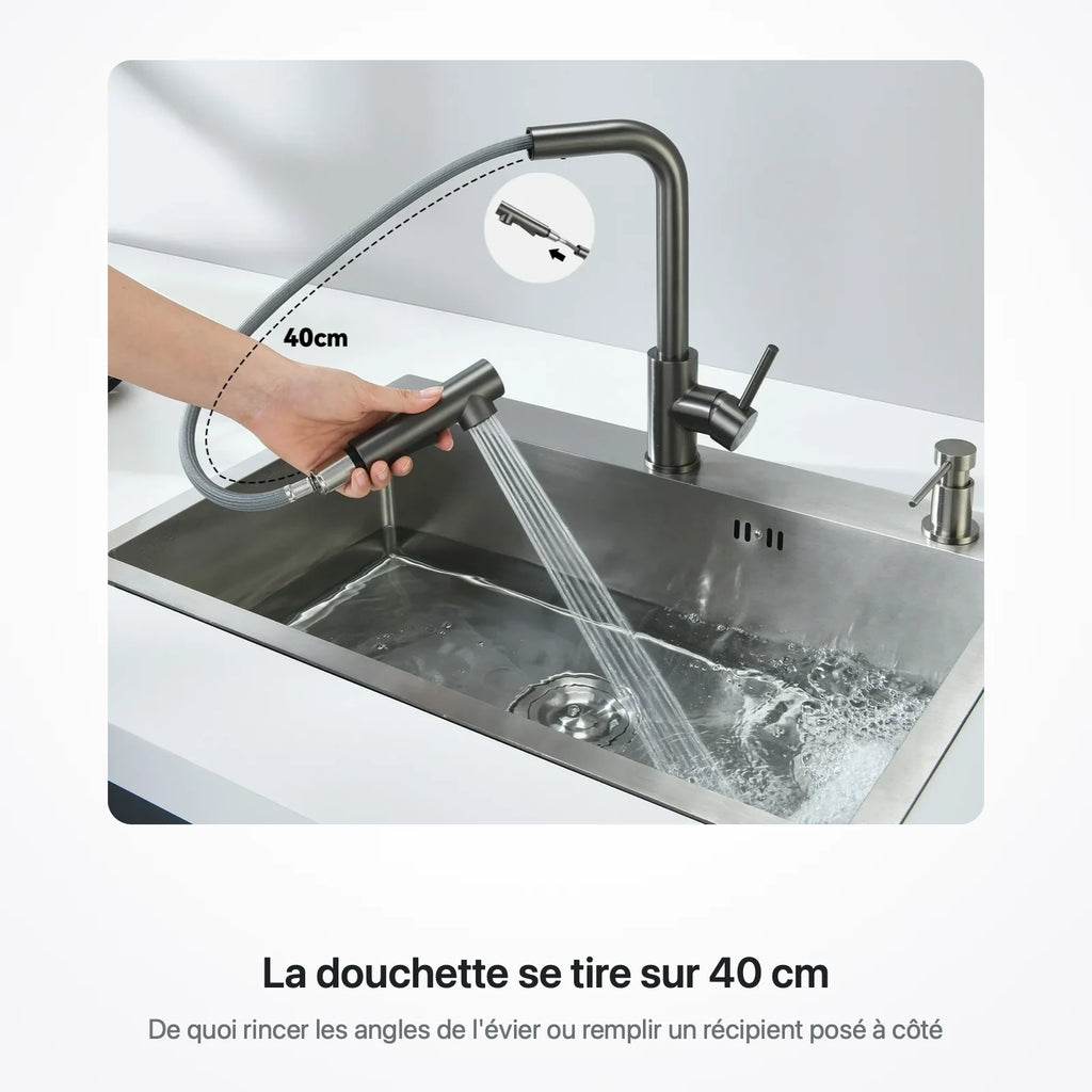 Main tirant la douchette du robinet sur 40 cm au-dessus d'un évier en inox