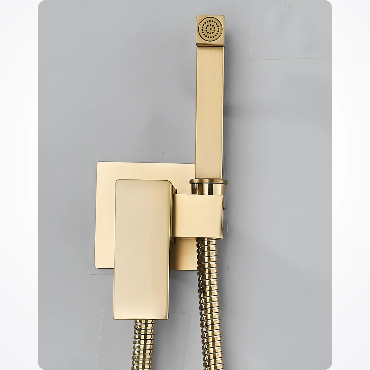 Robinet pour douchette WC or brossé monté au mur, rosace carrée, douchette rangée à la verticale sur son support