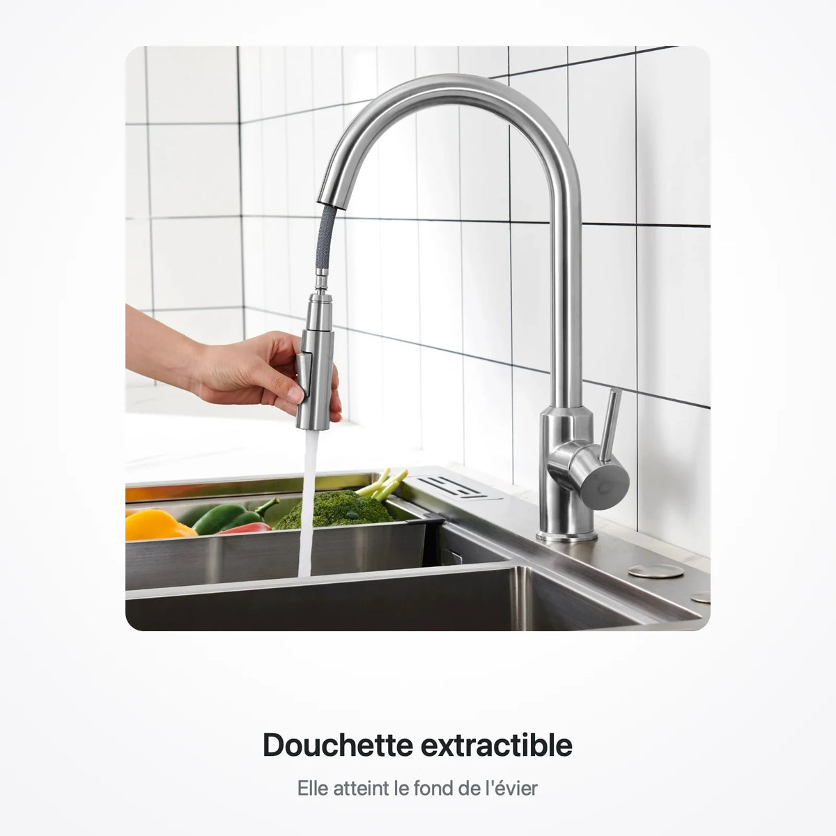 Main tenant la douchette extractible pour rincer des légumes au fond de l'évier