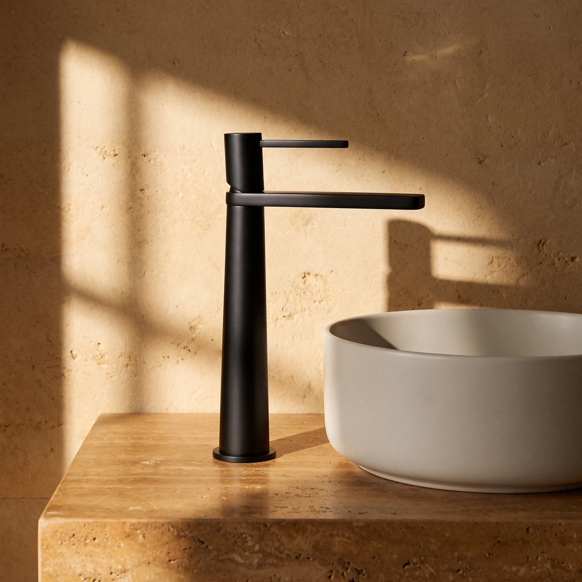 Mitigeur de lavabo haut en laiton noir mat, devant une vasque ronde à poser