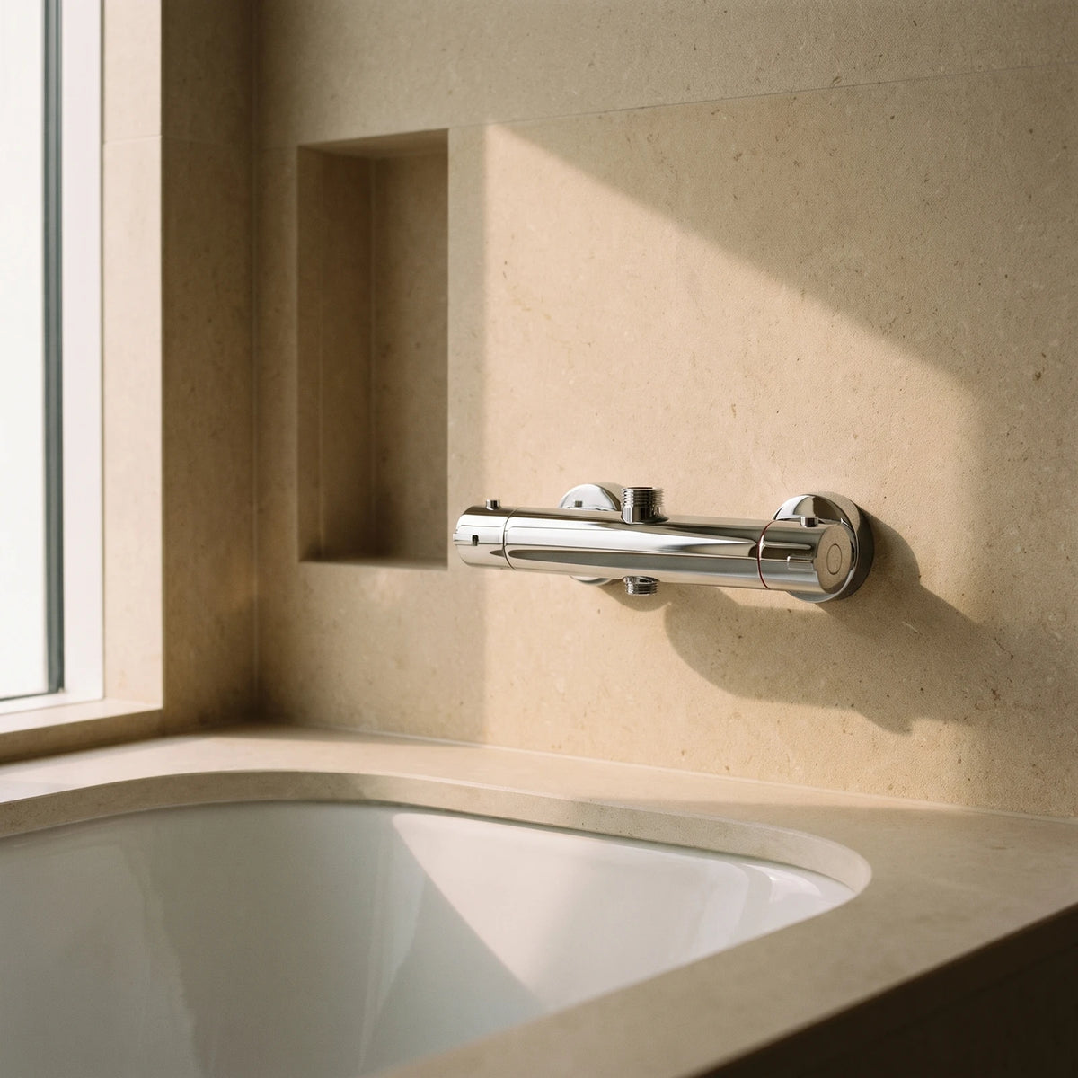 Robinet thermostatique de douche chromé monté sur un mur en pierre calcaire, au-dessus d'une baignoire encastrée